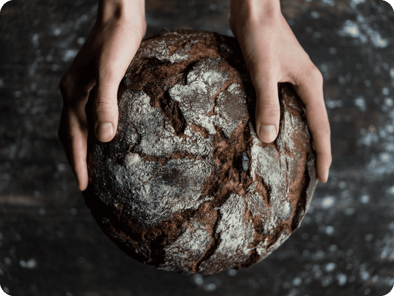 Rustikales Bauernbrot mit knuspriger Kruste in den Händen gehalten